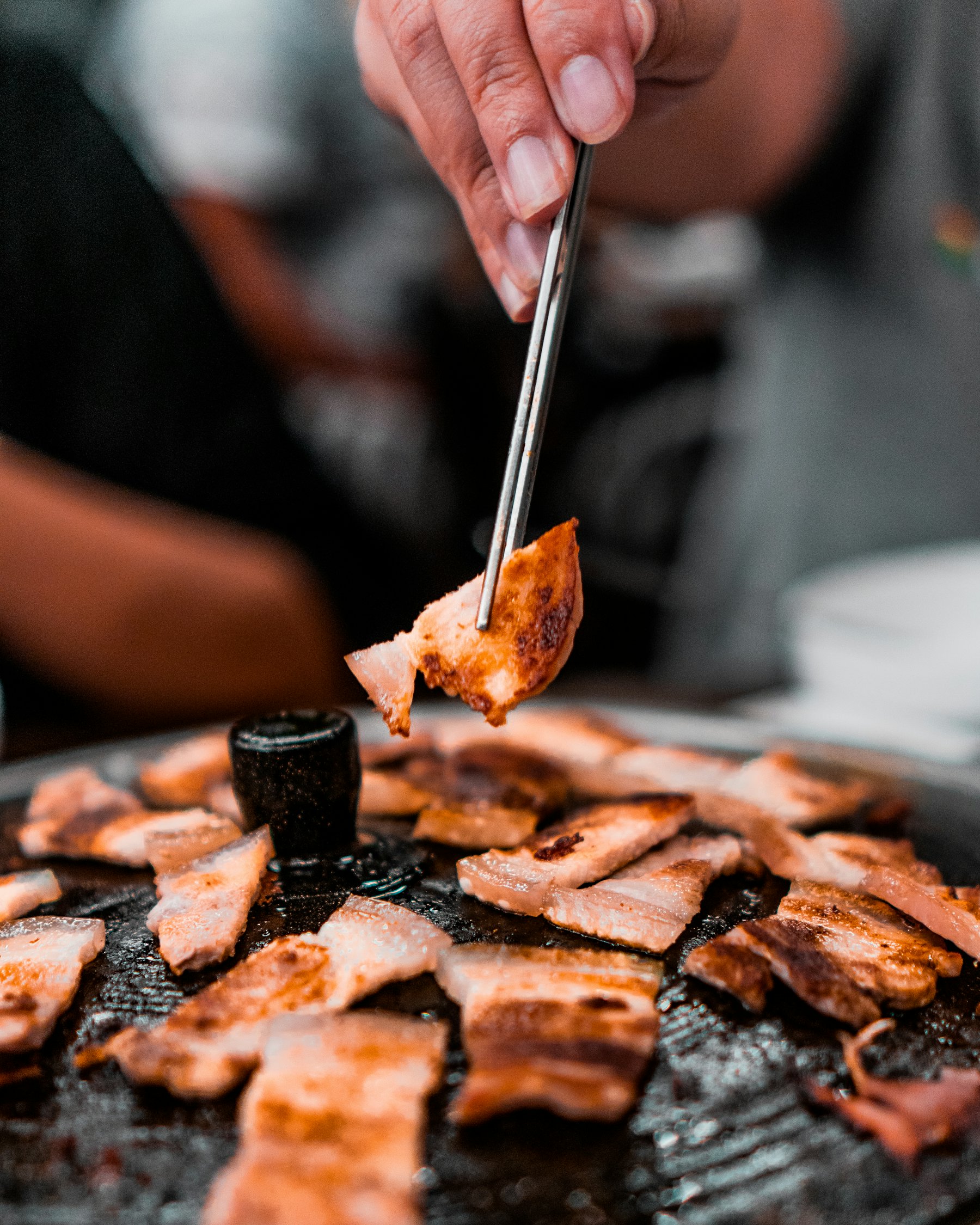 Vlees wordt met een tang van de grill gehaald