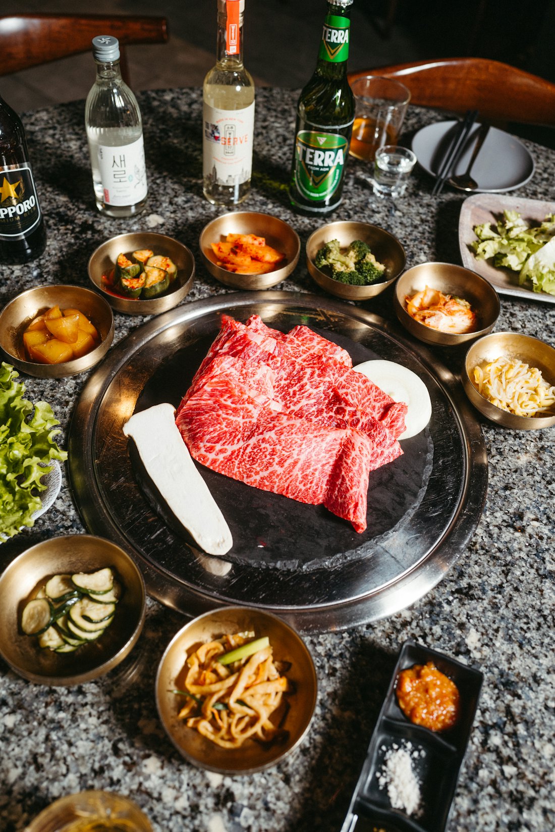 Tafel vol Koreaanse bijgerechten rond de grill